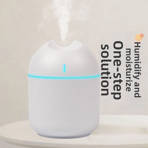 Close-up of portable mini humidifier with blue LED light ring emitting fine water mist