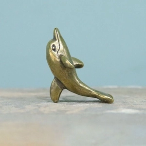 Detail of vintage brass dolphin figurine with distressed antique finish and texture