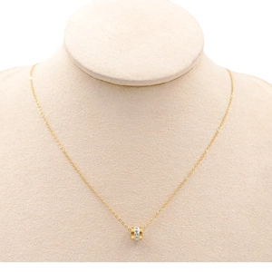 Elegant gold titanium steel cylinder necklace with sparkling crystals on a display stand