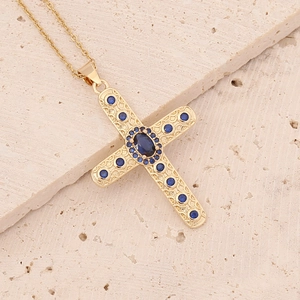 Detail of 18K gold cross necklace featuring deep blue zircons on a natural stone base