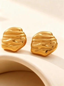 Macro detail of 18k gold plated earrings featuring irregular lava wave textures and metallic shine