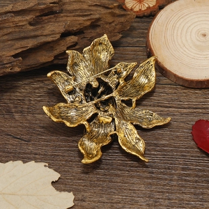 Vintage gold flower brooch with rhinestone detail, back view on a rustic wooden table