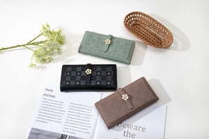 Detailed flat lay of checkered long wallets with flower clasps in green black and brown