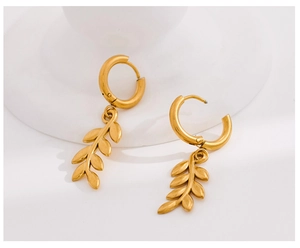 Detail of golden wheat leaf earrings with brushed metal texture on white background