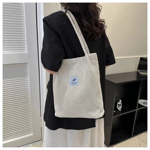 Lifestyle shot of white corduroy shoulder bag showing texture and strap length