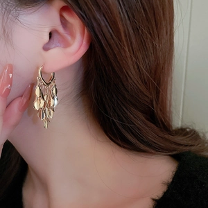 Close-up of golden multi-layered leaf tassel earrings with polished metallic finish