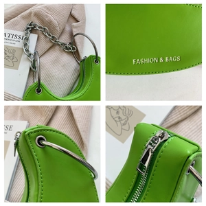 Detail of green leather baguette bag featuring silver ring handle and chain strap