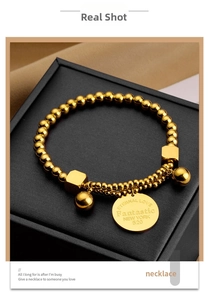 Detailed macro of gold bead bracelet featuring Eternal Love engraved charm on jewelry box