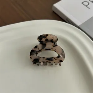 Detailed close-up of small tortoiseshell acetate hair claw clip on ceramic dish