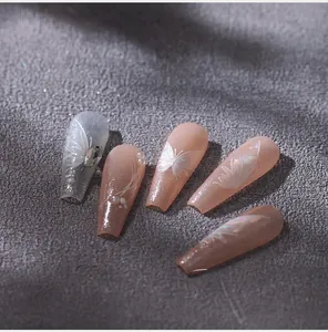 Gros plan d'ongles adhésifs cercueil avec nœuds argentés et détails strassés