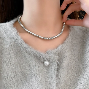 Detail of silver gray pearl necklace on model neck with grey knit cardigan texture