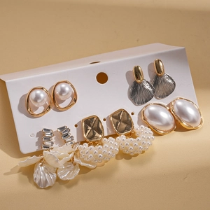 Gros plan de 5 paires de boucles d'oreilles perles baroques dorées et argentées sur carte