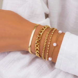 Detail of five-piece gold bracelet set with pearl accents and layered chain designs