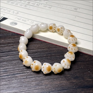 Detailed view of charred cat paw bodhi root beads on dark wood with calligraphy