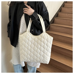 Detail of white quilted tote bag featuring classic diamond stitching and puffy nylon texture
