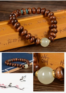 Détail de perles de prière en bois sombre avec accent vert et pierre de jade blanche