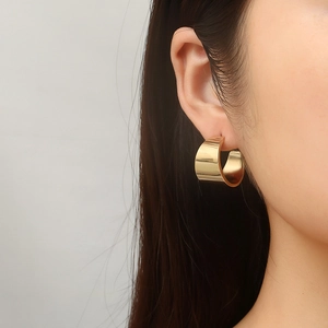Minimalist gold wide C-shape hoop earrings on model featuring a smooth polished surface