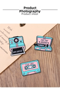 Detailed view of vintage enamel pins featuring camera, record player, and cassette tape