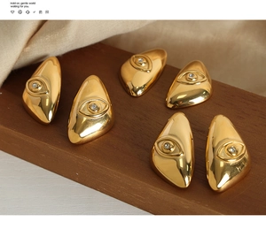 Macro shot of 18k gold devil's eye earrings with cubic zirconia on a wooden display stand