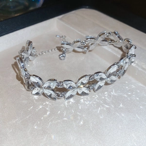 Detailed close-up of a silver leaf bracelet with crystals inside a beige jewelry gift box