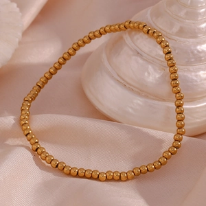 Detail view of 18K gold plated beaded stretch bracelet on silk with seashells