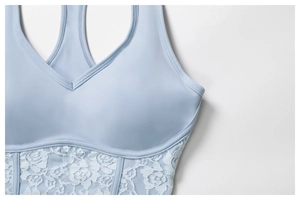 Close-up of light blue yoga top featuring intricate white rose lace trim and V-neckline