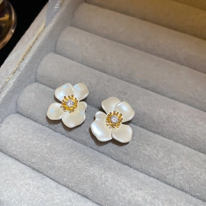 Detail view of flower earrings with white petals and zircon center in a velvet box