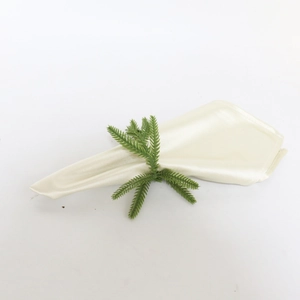 Close-up of artificial pine needle napkin ring with a folded beige fabric napkin