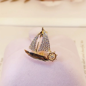 Macro detail of golden sailboat brooch with sparkling crystals and fine rudder design
