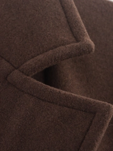 Gros plan sur la texture de la laine et les coutures de précision du manteau marron