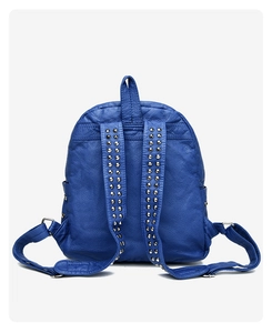 Detail of dark blue leather backpack straps with decorative silver metal rivets and stitching