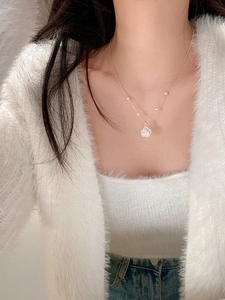 Close-up of golden flower pendant necklace with elegant pearls on a female model