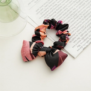 Close-up of floral pattern bow scrunchie on vintage newspaper and green glass background