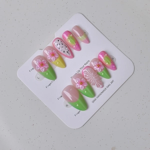 Detailed close-up of 3D floral almond nails with dragon fruit patterns and rhinestones