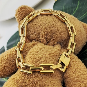Detail of a gold bamboo link chain bracelet displayed on a plush teddy bear