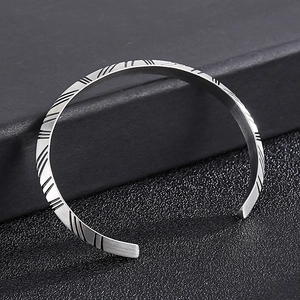 Macro detail of men's titanium steel open cuff featuring vintage rhombus lattice patterns