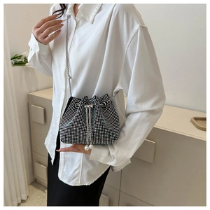 Detail of black bucket bag featuring silver studs and pearl drawstring closure