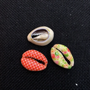 Macro view of natural hand-painted shells with pink plaid and floral patterns for DIY jewelry
