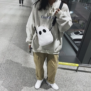 Outdoor street style view of a cute ghost-shaped white PU crossbody bag with black eyes