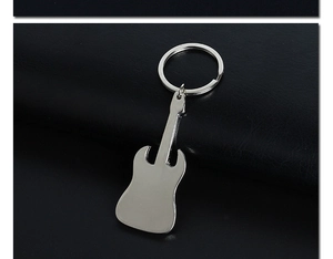 Close-up of a silver metal guitar keychain with a polished finish on dark leather surface