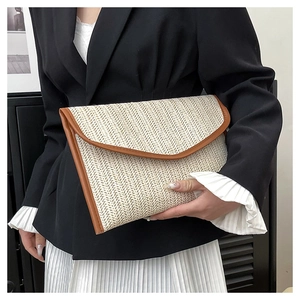Detail of hand-woven straw envelope clutch with brown leather trim and flap closure