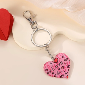 Pink heart-shaped acrylic keychain with LOVE patterns and metal clasp on cream background