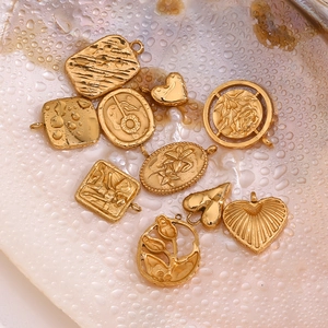 Macro view of vintage 18K gold-plated sunflower and heart charms on pearly pink surface