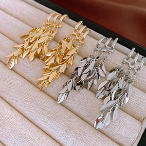 Three-layer geometric leaf tassel earrings in gold and silver finish on a beige display