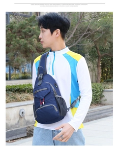 Detail view of dark blue nylon sling bag with mesh water bottle pocket and red cord accent