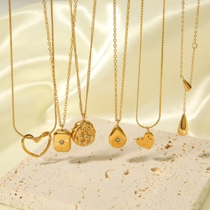 Gold layered necklaces featuring heart and teardrop pendants with zircons on silk background