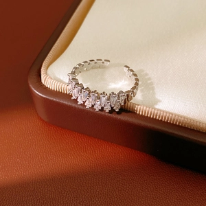 Macro detail of silver adjustable ring with trapezoid zircons on brown leather box
