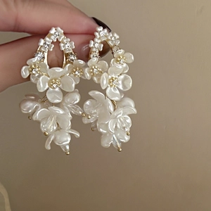 Detail of flower earrings with shell petals, zircon accents and gold tassels