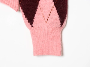 Close-up of pink and brown argyle knit cardigan showing ribbed cuffs and soft texture