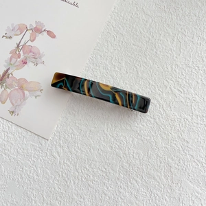 Detail view of rectangular marbled acetate hair clip with metal spring back clip